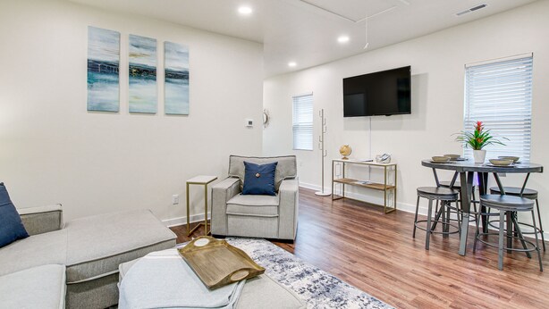 A modern living room with a grey sofa, a grey armchair, a coffee table, and a TV mounted on the wall. - Dog-Friendly Sheboygan Home - 1 Mi to Town! (Sheboygan)