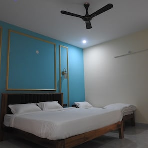 A bedroom with a bed, a ceiling fan, and a mirror. - Nueva Boarding And Lodging (Ramanagara)