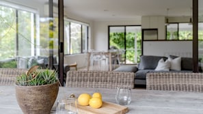 Ein modernes Wohnzimmer mit großem Fenster, Korbmöbeln, einem Blumentopf und einem Tisch mit Zitronen und Gläsern.