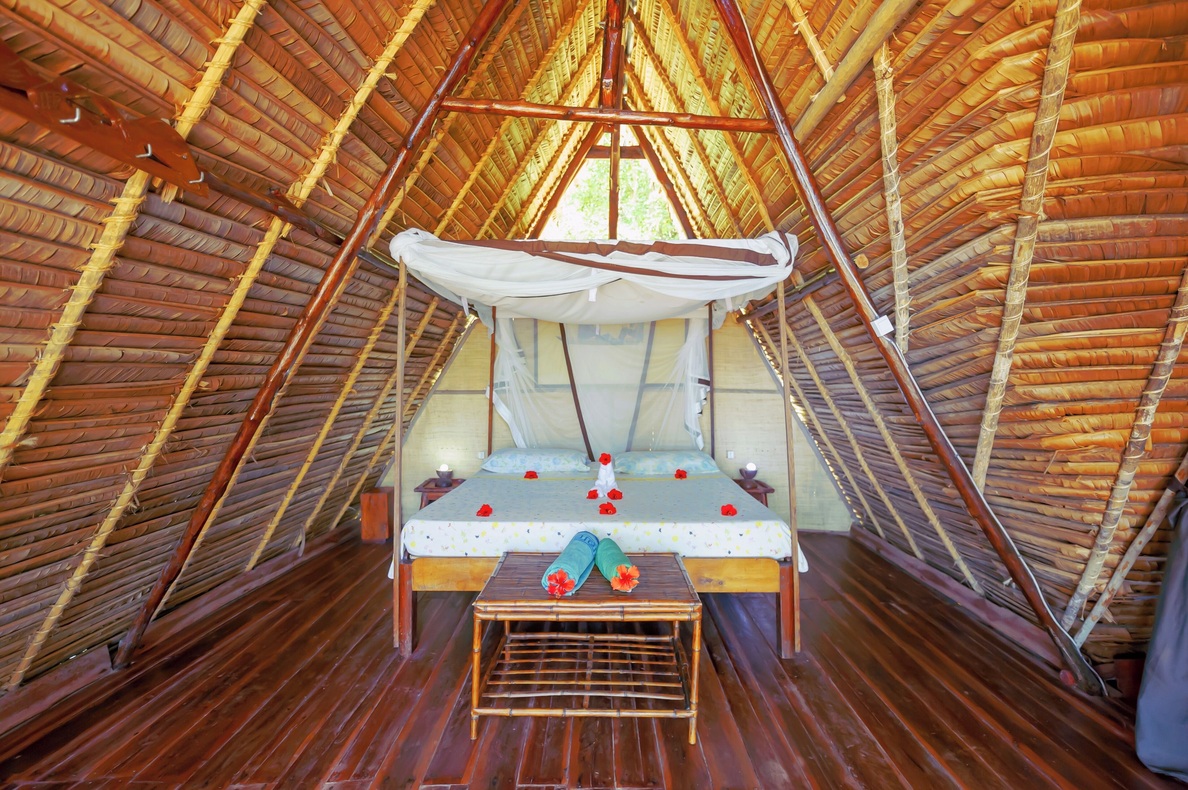 Una habitación acogedora con techo triangular, una cama, almohadas y una pequeña mesa.