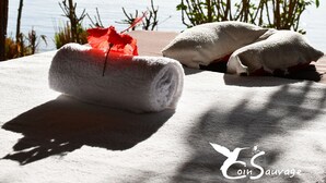 A beachside relaxation area with towels and a red flower, overlooking the sea. - Coin Sauvage (Nosy Be)