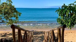 A wooden pathway leading to a beach with a clear view of the ocean. - Coin Sauvage (Nosy Be)