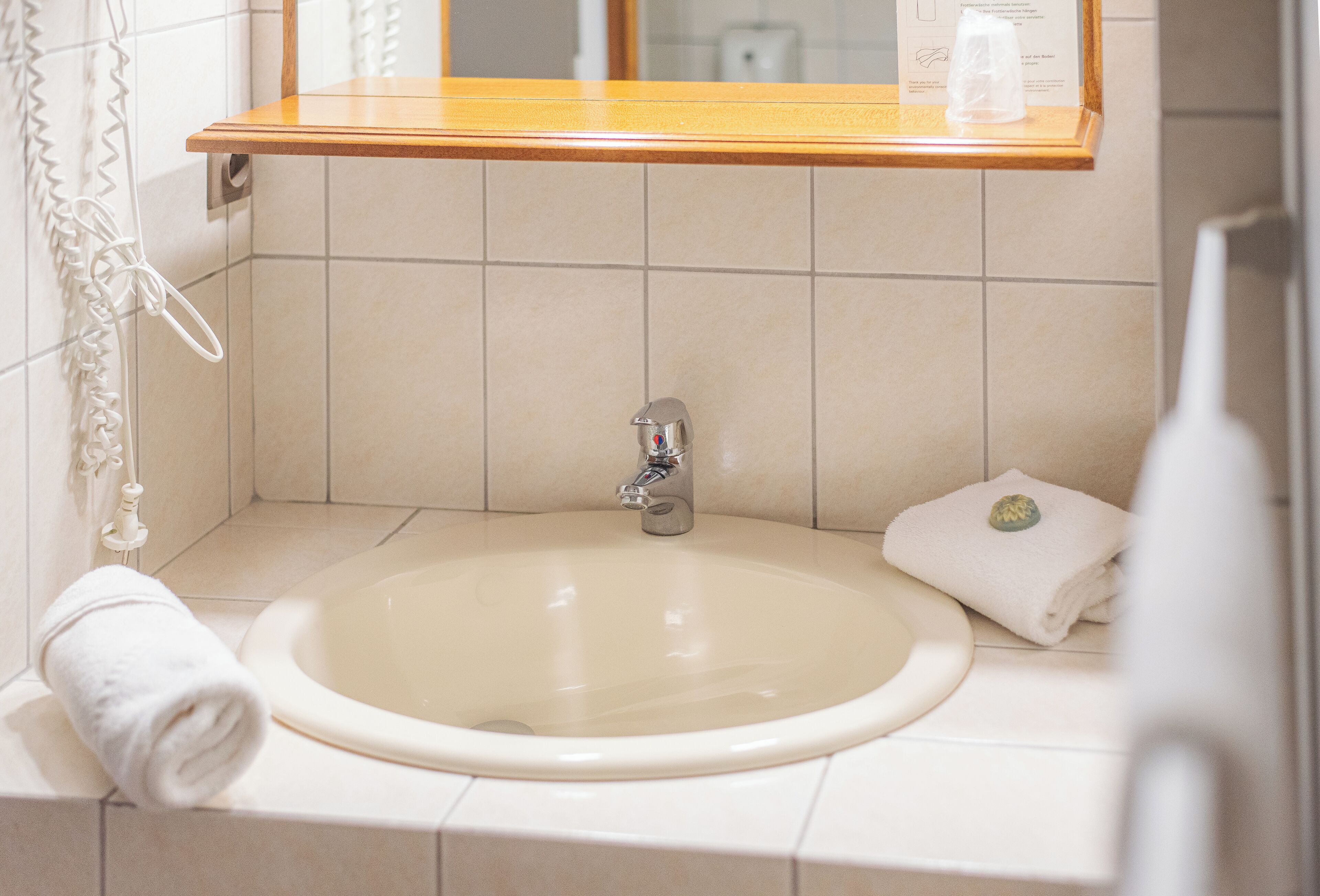 A bathroom with a sink, mirror, and towel.