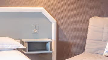 Hotelkamer met een bed, een stoel, een nachtkastje en een muur met een herringbone motief.