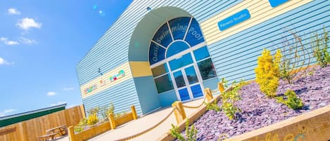 A building with a blue exterior, an arched entrance, and a sign for an interactive wall and fitness studio.