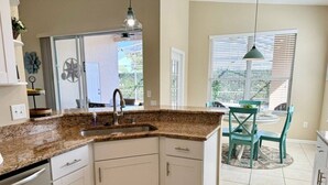 A kitchen with white cabinets, granite countertops, and a built-in sink. - Sunshine 3bdrm pool house near Disney (Kissimmee)