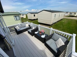 A deck with outdoor furniture and a view of mobile homes in the background. - MP413 - Camber Sands Holiday Park (Camber)