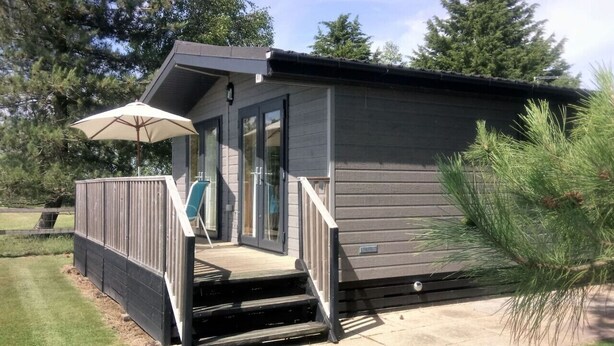 Une petite cabane à un seul étage, dotée d’un porche couvert et d’une porte-fenêtre coulissante.