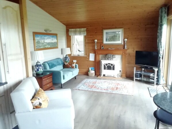 Ein gemütliches Wohnzimmer mit Kamin, einer Couch, einem Fernseher und einem Essbereich.
