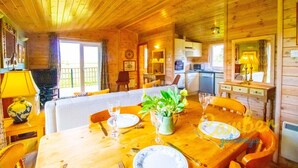 A wooden cabin interior with a dining area, kitchen, and living space. - Rainbow Petty - Pine lodge - Kent countryside (Brookland)
