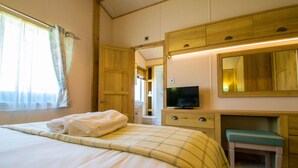 Ein Hotelzimmer mit einem Bett, einem Fernseher, einem Holzschrank und einem Schreibtisch mit Stuhl.