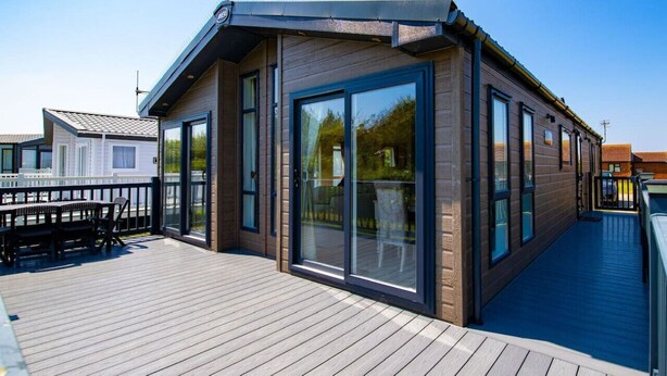 Ein modernes Gebäude mit großen Glasüren und einer Holzterrasse.