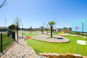A golf course with a blue building, trees, and a clear sky. - SBL19 - 3B - Delta Serenity (Camber)