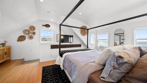 A bedroom with a bed, a TV, a window, and a view of the sea. - #StayInMyDistrict SurfsideHaven (Rockaway Beach)