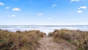 A sandy path leading to the ocean with tall grass on either side. - #StayInMyDistrict SurfsideHaven (Rockaway Beach)