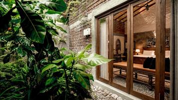 Una habitación acogedora con una cama de madera, una mesita pequeña y una ventana con vistas a un jardín.
