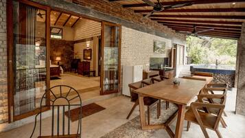 Un comedor amplio con una gran mesa de madera y sillas, una pared de piedra y vistas al exterior.