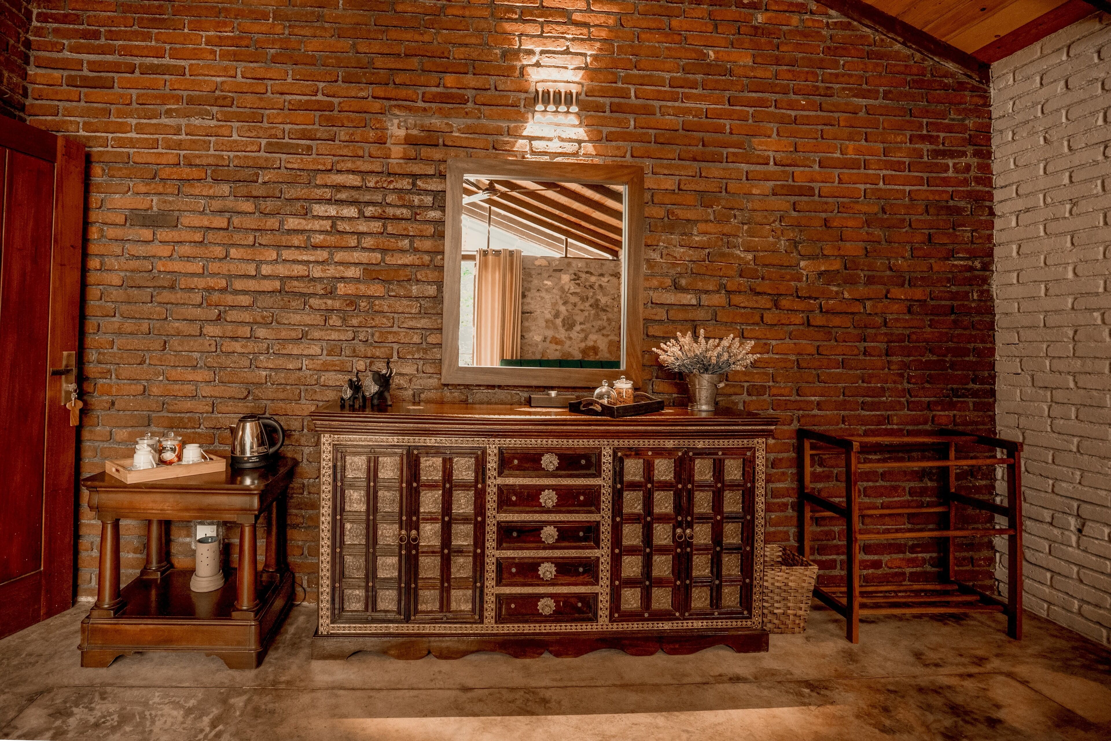 A rustic room with a brick wall, wooden cabinet, and a mirror.