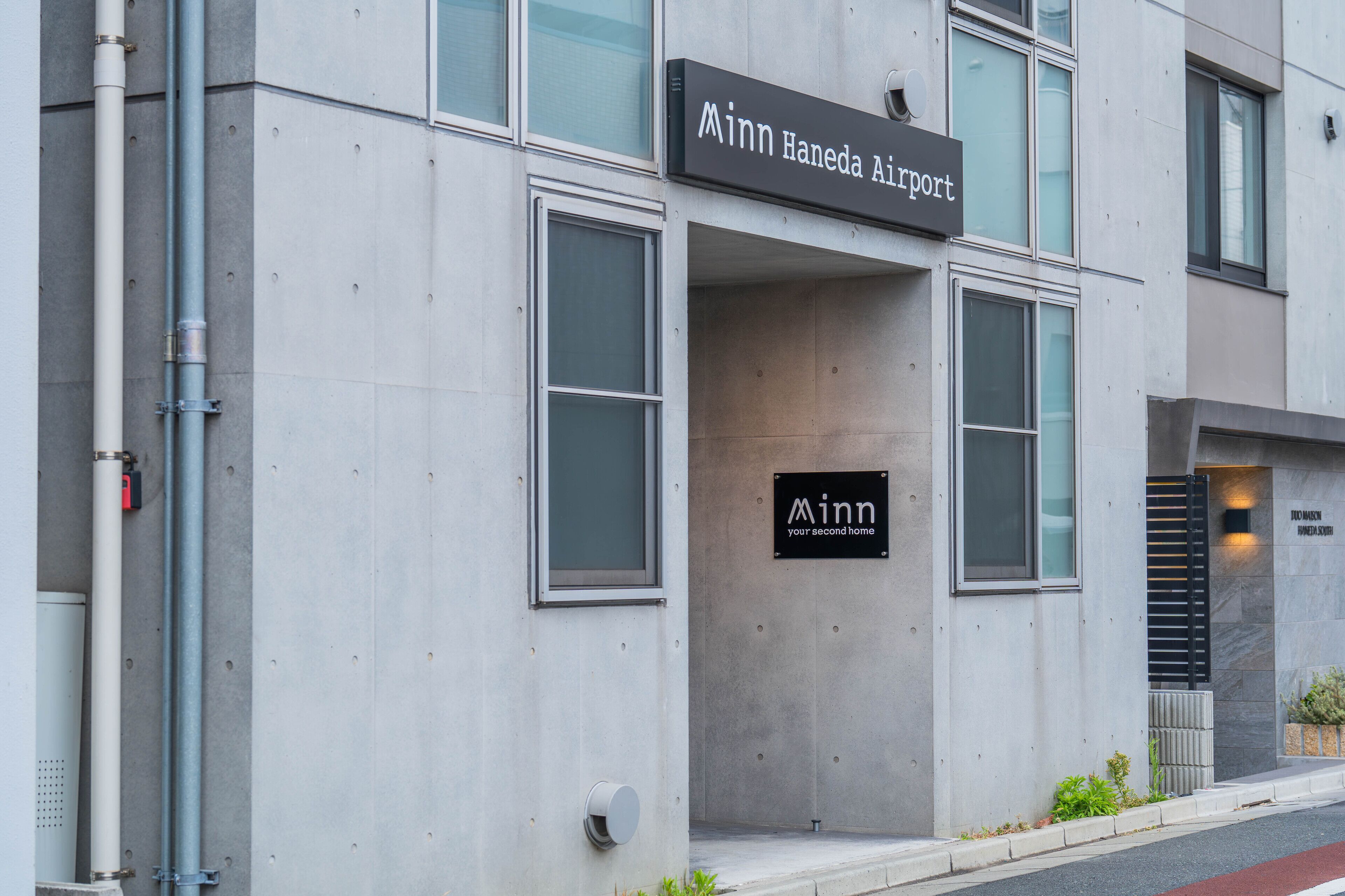 A building with a sign reading "Minn Haneda Airport" and another sign below it that says "Minn your second home."