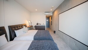 Une chambre d’hôtel équipée d’un lit, d’un bureau, d’une kitchenette et d’un grand écran.