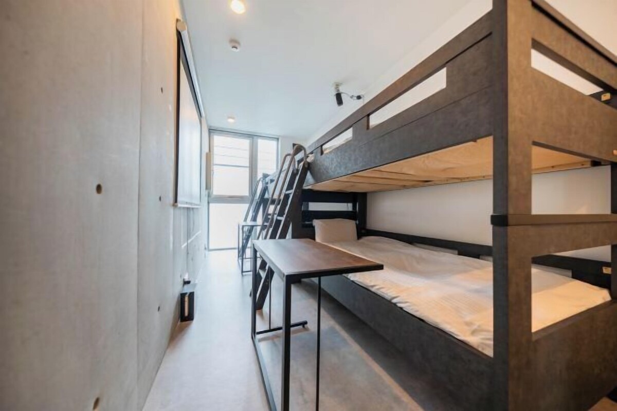 A bunk bed room with a window, a desk, and a ladder.