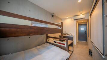 A bunk bed with a desk and chair, a small kitchenette, and a door leading to another room.
