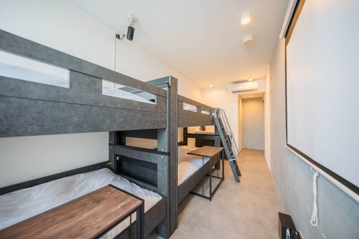 A bunk bed room with a ladder, a desk, and a small shelf.