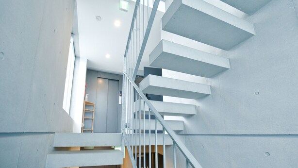 Un escalier moderne au design minimaliste, doté d’une rampe en métal et de marches en béton.