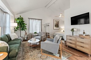 Una sala de estar moderna con un sofá, sillones, una mesa de centro y un televisor montado en la pared.