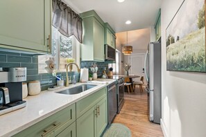 Una cocina moderna con armarios verdes, horno empotrado y refrigerador.