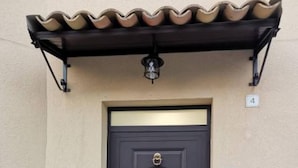 A dark brown door with a gold handle and a decorative design, flanked by two numbered mailboxes and a small light fixture above. - Lido Apartment Near the sea - air Conditioned (Noto)