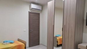 A hotel room with a bed, a wardrobe, and an air conditioning unit. - Lido Apartment Near the sea - air Conditioned (Noto)