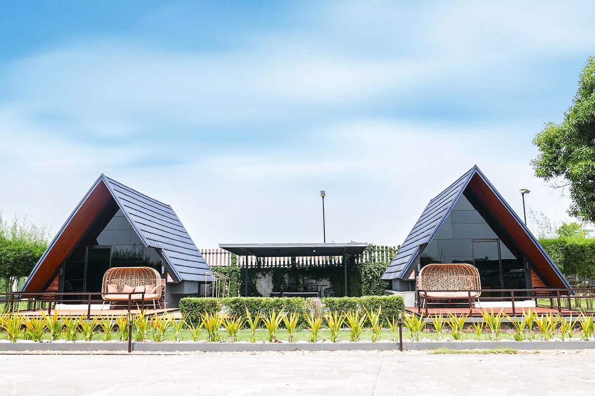 Deux bâtiments modernes, dotés de toits triangulaires, avec des espaces de détente en plein air et une structure centrale.