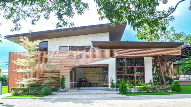 A modern building with a sloped roof, large windows, and a covered entrance area.
