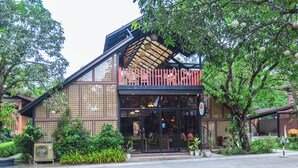 A building with a glass storefront, outdoor seating, and a red fence.
