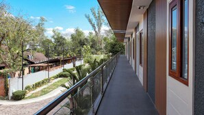 A balcony with a view of a landscaped area, a building with large windows, and a clear sky.