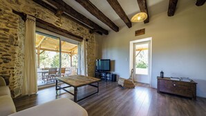 A spacious living area with a wooden table, a sofa, a TV, and a wicker chair. - Nouyritte, this house has everything you are looking for! (Villesèque)