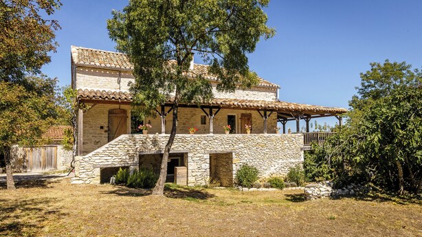 A stone house with a tiled roof, a wooden porch, and a small garden area. - Nouyritte, this house has everything you are looking for! (Villesèque)