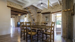 A spacious dining area with a large wooden table and chairs, stone walls, and exposed wooden beams. - Nouyritte, this house has everything you are looking for! (Villesèque)
