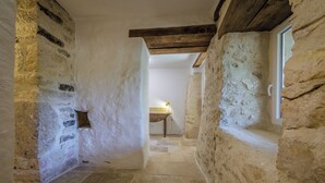 A narrow stone corridor with a rustic wooden ceiling and a small table with a lamp in the distance. - Nouyritte, this house has everything you are looking for! (Villesèque)