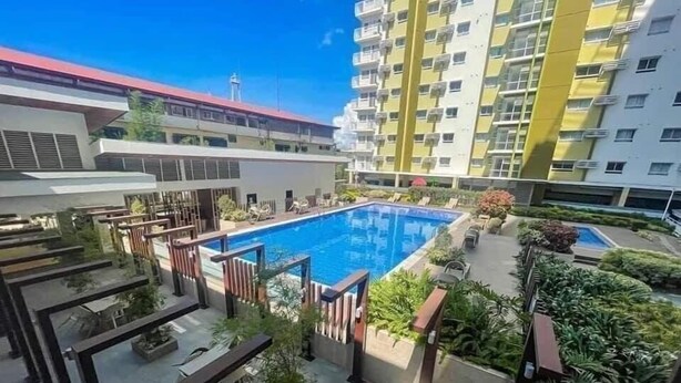 A rooftop pool area with a clear view of the surrounding buildings, including a high-rise with yellow and white facades. - MESAVERTE STUDIO UNIT (Cagayan de Oro)