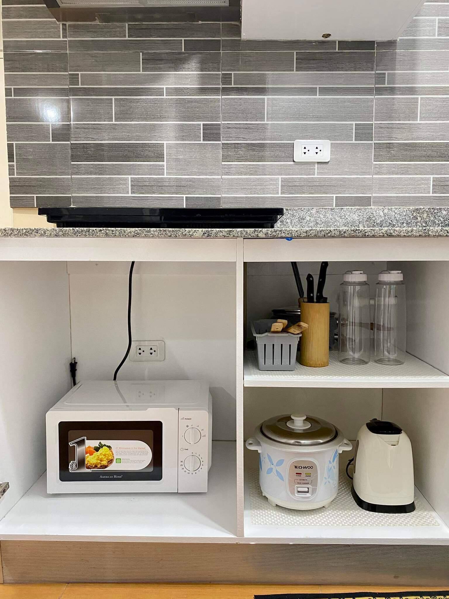 A kitchen with a microwave, a slow cooker, and a coffee maker on the countertop.