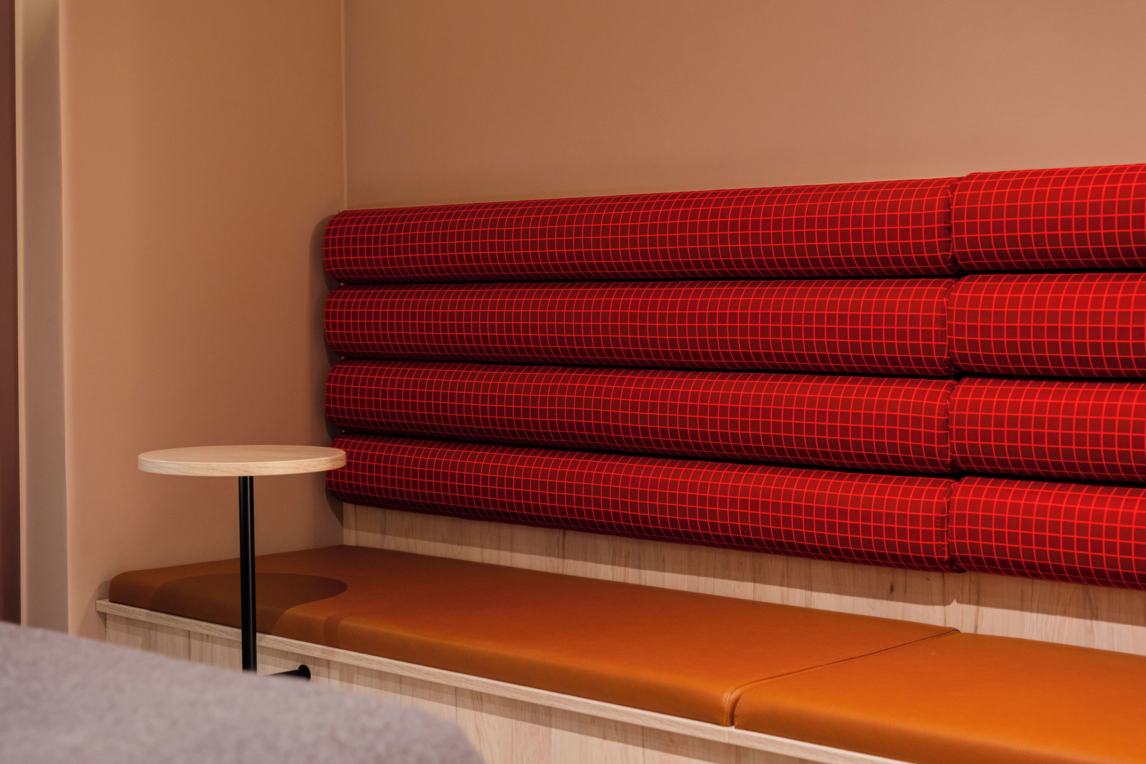 A seating area with red patterned cushions and a small round table.