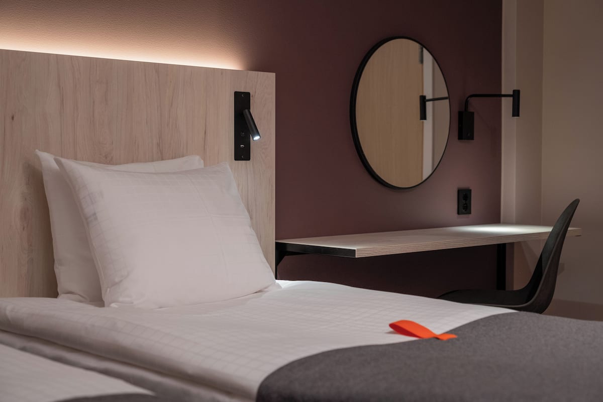 A hotel room with a bed, a desk, and a chair.