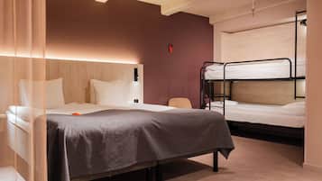 Habitación de hotel con una cama individual, una cama litera, una mesita de noche y una silla.