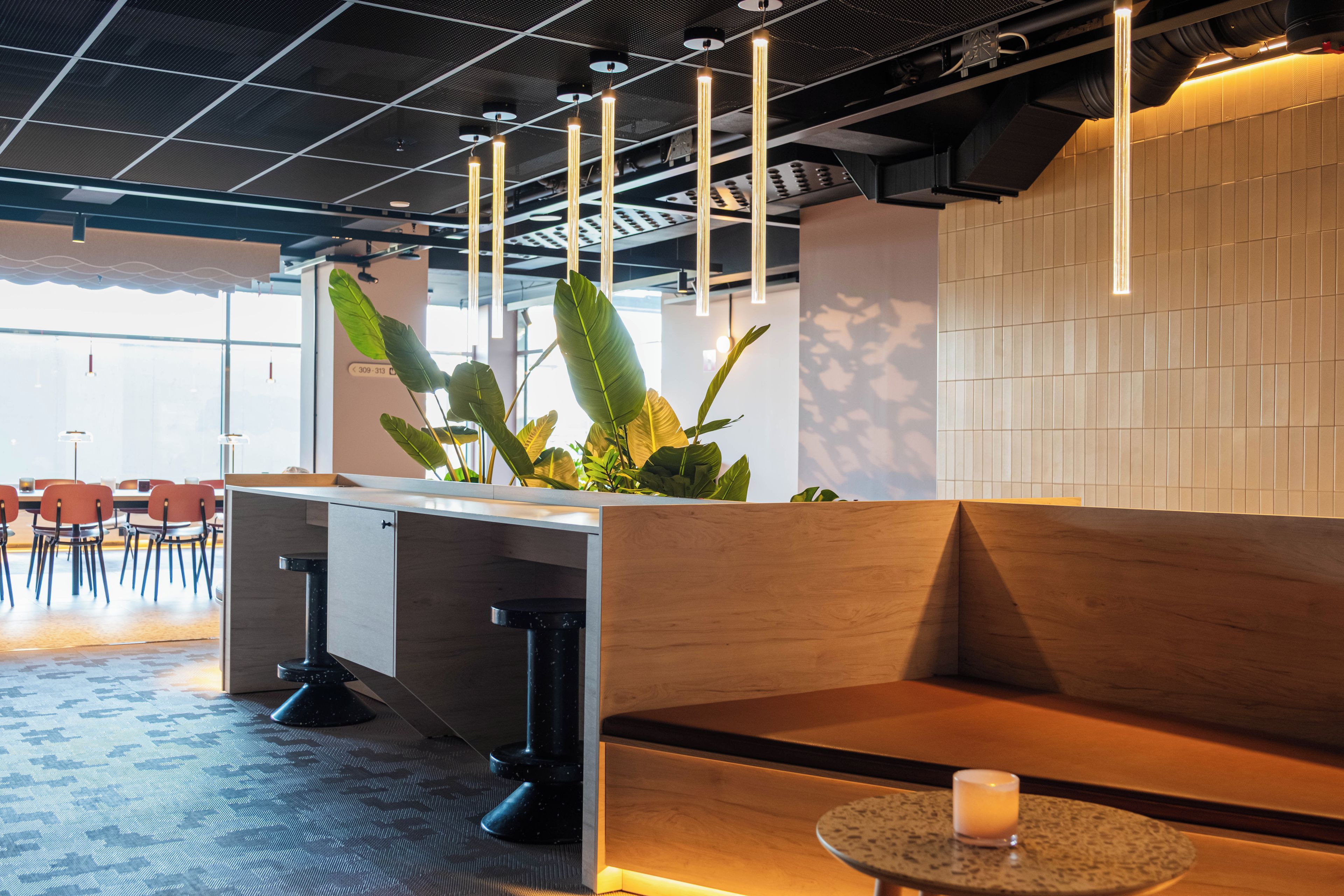 Een modern interieur met een houten bankje, een klein rond tafeltje met een kaars en een plant.