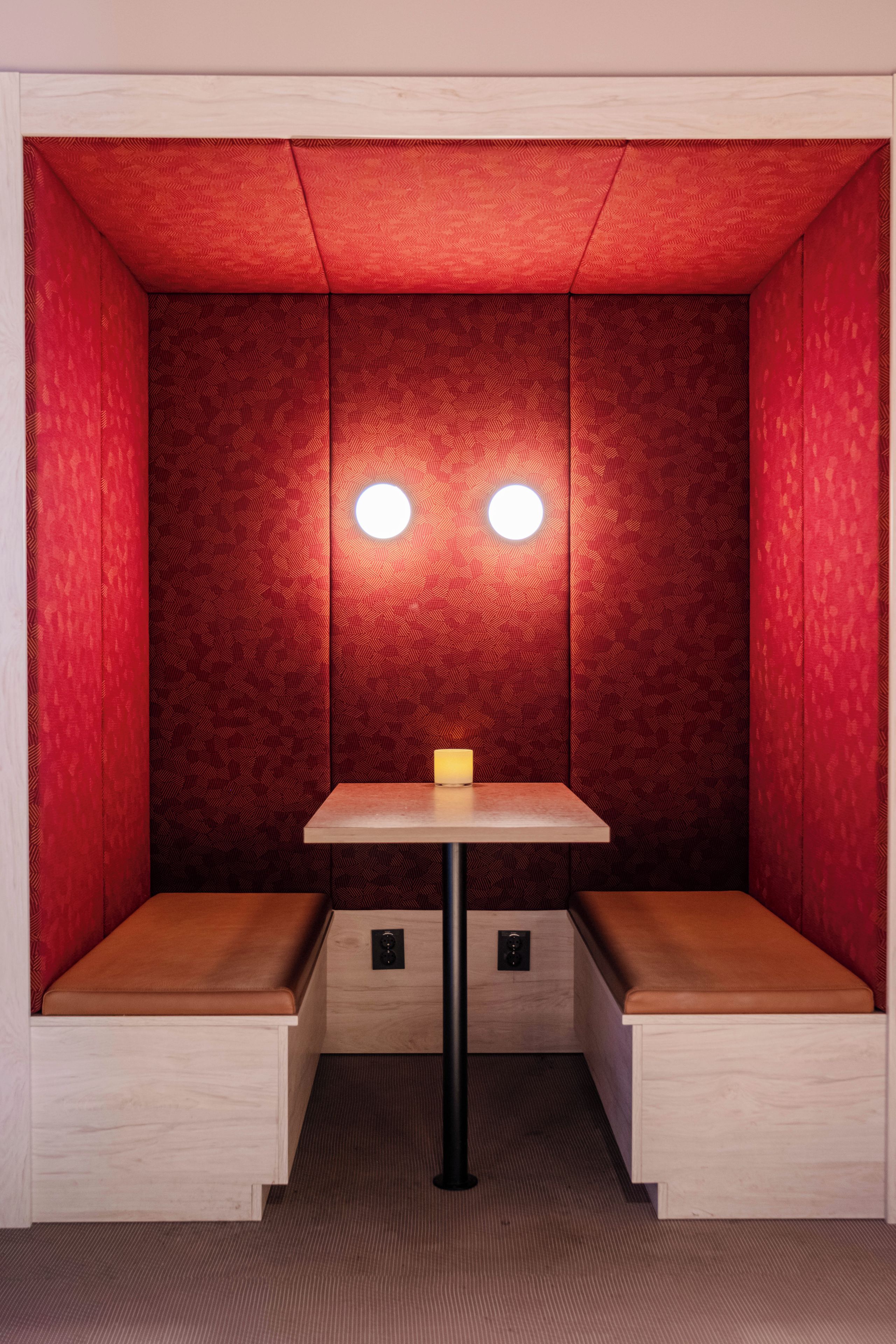 A small, enclosed room with a bench, a table, and two wall-mounted lights.