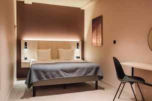 Une chambre d’hôtel moderne équipée d’un lit, de tables de chevet, d’un bureau et d’une chaise.