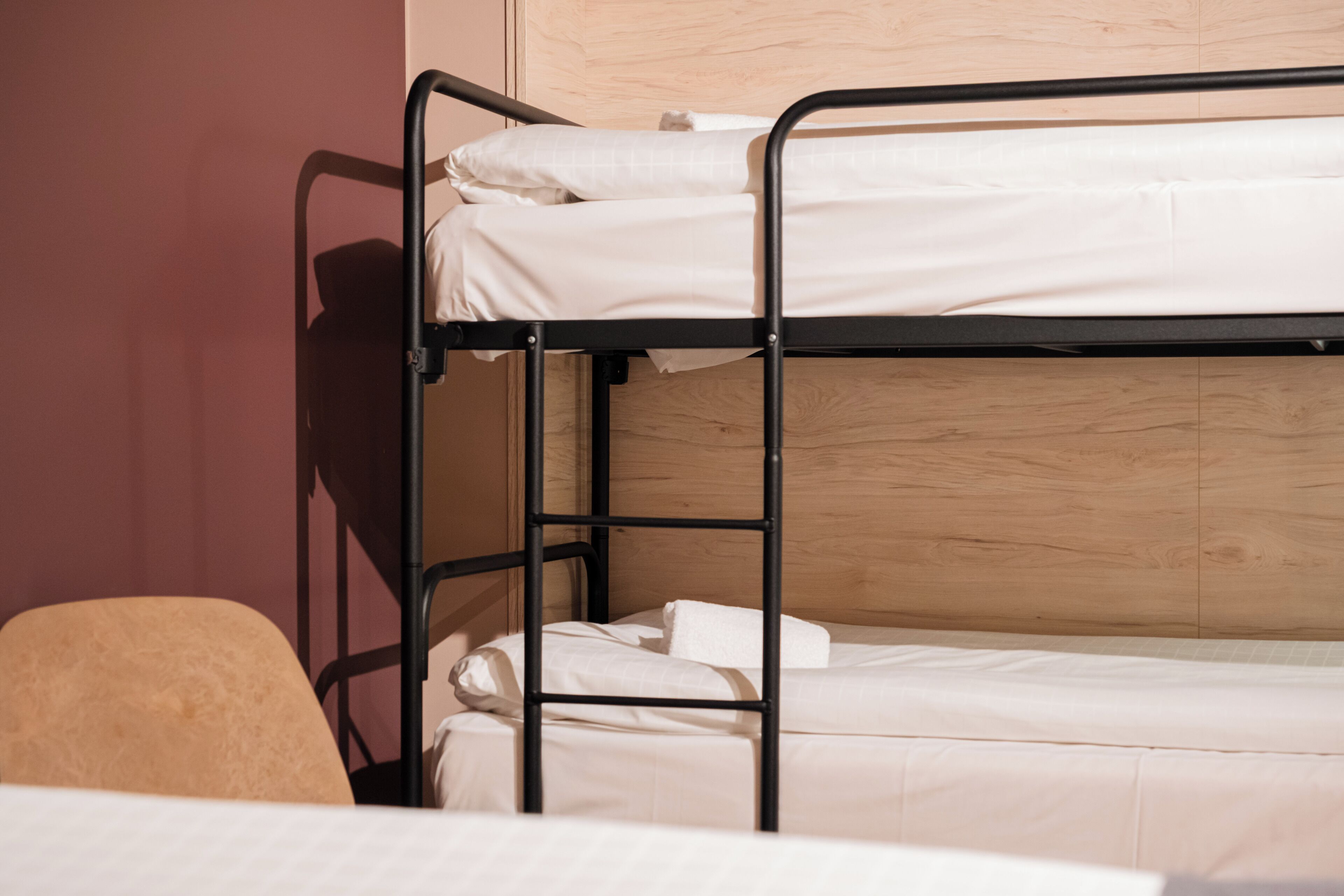 A bunk bed with white bedding and a wooden headboard.