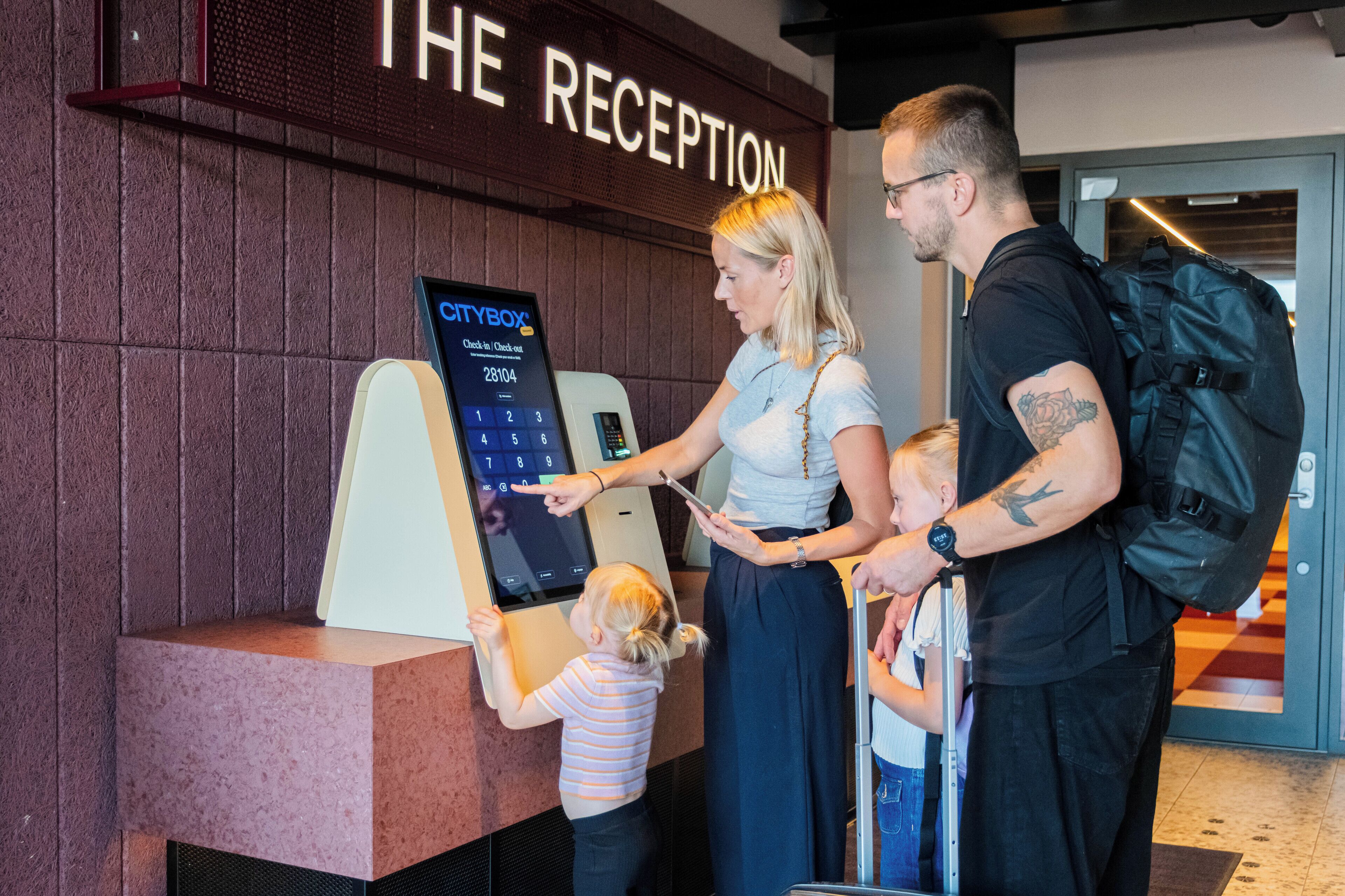 A reception area with a digital check-in kiosk and a sign that reads "THE RECEPTION".